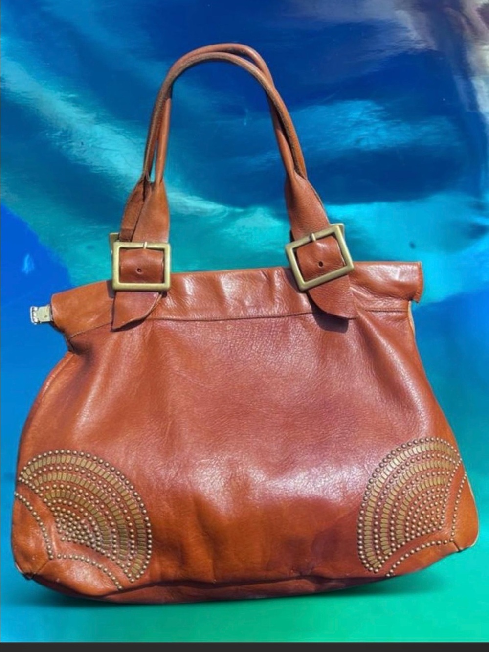 Brown leather handbag with studded accents and gold color hardware